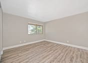 Thumbnail 13 of 43 - Empty room with wooden flooring and a window.
