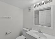 Thumbnail 20 of 27 - A white bathroom with a toilet, sink, mirror and lights.