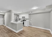 Thumbnail 16 of 27 - A kitchen with white cabinets and a wooden floor.