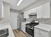 Thumbnail 15 of 27 - A kitchen with white cabinets and stainless steel appliances.