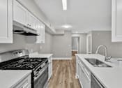 Thumbnail 13 of 27 - A kitchen with a stove top oven and a sink.