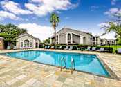 Thumbnail 24 of 27 - A swimming pool surrounded by lounge chairs and palm trees.