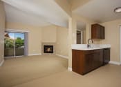 Thumbnail 21 of 31 - an empty living room with a fireplace and a kitchen