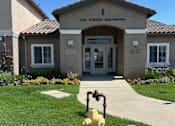 Thumbnail 2 of 27 - A yellow fire hydrant is in front of the entrance to Los Arboles Apartments.