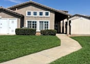 Thumbnail 3 of 27 - A house with a white garage door and a brown roof.