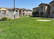 Thumbnail 6 of 27 - A grassy area in front of apartment buildings.
