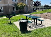 Thumbnail 26 of 27 - A green trash can sits next to a green picnic table.