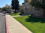 Thumbnail 18 of 27 - A sidewalk runs along a grassy area in front of apartment buildings.