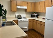 Thumbnail 12 of 27 - A kitchen with wooden cabinets and white appliances.
