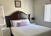 Thumbnail 9 of 27 - A bed with a white comforter and a wooden headboard.