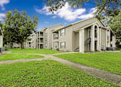 Thumbnail 8 of 27 - A row of apartment buildings with green lawns in front.