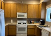 Thumbnail 11 of 27 - A kitchen with wooden cabinets and white appliances.