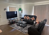 Thumbnail 5 of 25 - A living room with a black couch and a flat screen TV.