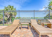 Thumbnail 7 of 15 - A patio with a table and chairs overlooking a body of water.