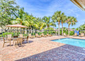 Thumbnail 2 of 15 - A pool area with a table and chairs and a fence.
