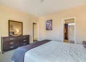 Thumbnail 9 of 25 - a bedroom with a bed and a dresser and a mirror
