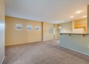Thumbnail 22 of 25 - the living room and kitchen of an empty home with carpeted floors and a counter