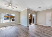 Thumbnail 11 of 23 - an empty living room with wood floors and a ceiling fan