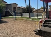 Thumbnail 7 of 25 - A playground with a slide and palm trees in the background.