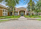 Thumbnail 14 of 19 - A brick pathway leads to a building entrance surrounded by greenery.