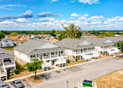 Thumbnail 2 of 25 - A sunny day at a residential complex with multiple houses and cars.