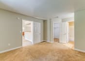 Thumbnail 2 of 25 - an empty living room with two open doors and a carpeted floor
