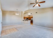 Thumbnail 13 of 30 - an empty living room with a ceiling fan and a kitchen