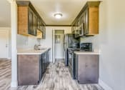 Thumbnail 8 of 17 - an empty kitchen with stainless steel appliances and wood flooring