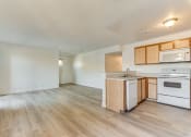 Thumbnail 14 of 32 - a kitchen and living room with hardwood floors and white walls at Pacific Harbors Sunrise Apartments, Las Vegas, Nevada