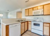Thumbnail 20 of 32 - a kitchen with wooden cabinets and white appliances at Pacific Harbors Sunrise Apartments, Las Vegas, NV