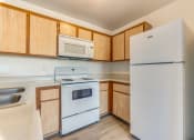 Thumbnail 25 of 32 - a kitchen with white appliances and wooden cabinets at Pacific Harbors Sunrise Apartments, Las Vegas, NV