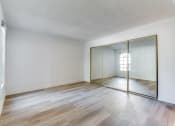 Thumbnail 5 of 32 - a bedroom with hardwood floors and a large mirror at Pacific Harbors Sunrise Apartments, Las Vegas, NV, 89142