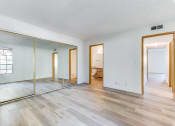 Thumbnail 17 of 32 - a bedroom with hardwood floors and a large mirror at Pacific Harbors Sunrise Apartments, Las Vegas, Nevada