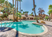 Thumbnail 6 of 32 - a swimming pool with palm trees and a house in the background at Pacific Harbors Sunrise Apartments, Las Vegas, NV, 89142
