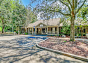 Thumbnail 14 of 25 - A house with a driveway and trees in front.