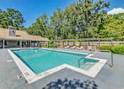 Thumbnail 1 of 25 - A swimming pool in a backyard with a house and trees in the background.