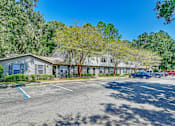Thumbnail 10 of 25 - A parking lot with a building and trees in the background.