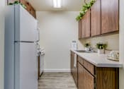 Thumbnail 5 of 13 - A kitchen with a refrigerator, wooden cabinets, and a sink.
