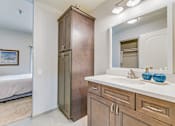 Thumbnail 13 of 28 - A bathroom with a wooden cabinet and a white countertop.