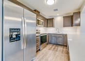 Thumbnail 14 of 28 - A modern kitchen with a stainless steel refrigerator and wooden cabinets.