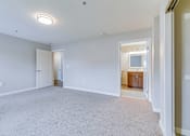 Thumbnail 11 of 28 - A large empty room with a carpeted floor and a doorway leading to another room.