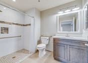 Thumbnail 21 of 28 - A white toilet sits in a bathroom with a white shower curtain.