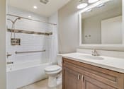 Thumbnail 20 of 28 - A white bathroom with a toilet, sink, and a shower with a glass door.
