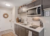 Thumbnail 1 of 15 - A kitchen with a white counter top and a white sink.