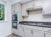 Thumbnail 5 of 28 - A kitchen with white cabinets and a granite countertop.