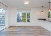 Thumbnail 9 of 28 - A room with a large window and wooden flooring.