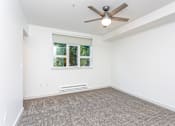 Thumbnail 10 of 28 - A room with a ceiling fan and a window with a view of trees.