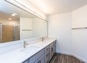 Thumbnail 11 of 28 - A bathroom with a white counter top and a large mirror.