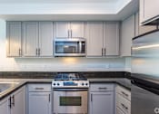 Thumbnail 16 of 28 - A modern kitchen with a stove top oven and microwave above it.