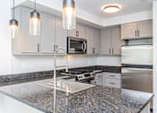 Thumbnail 17 of 28 - A kitchen with granite countertops and stainless steel appliances.